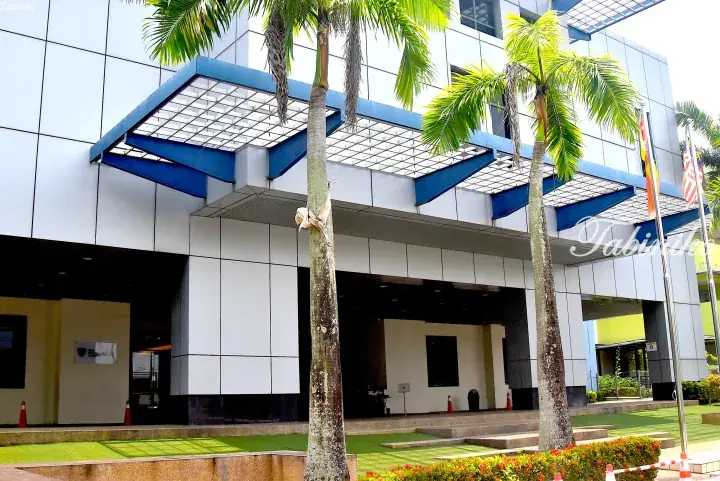 Modern building entrance with blue canopy and palm trees, Malaysia
