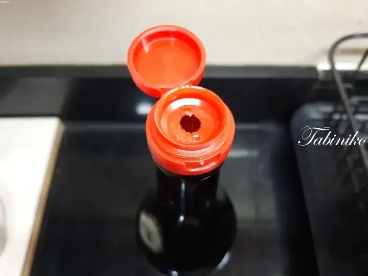 Top-down view of an open glass honey bottle with a yellow cap, showing golden honey inside.