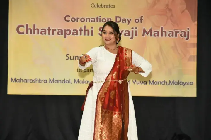 Woman in traditional attire performs on stage at the Chhatrapati Shivaji Maharaj Coronation Day celebration in Malaysia.
