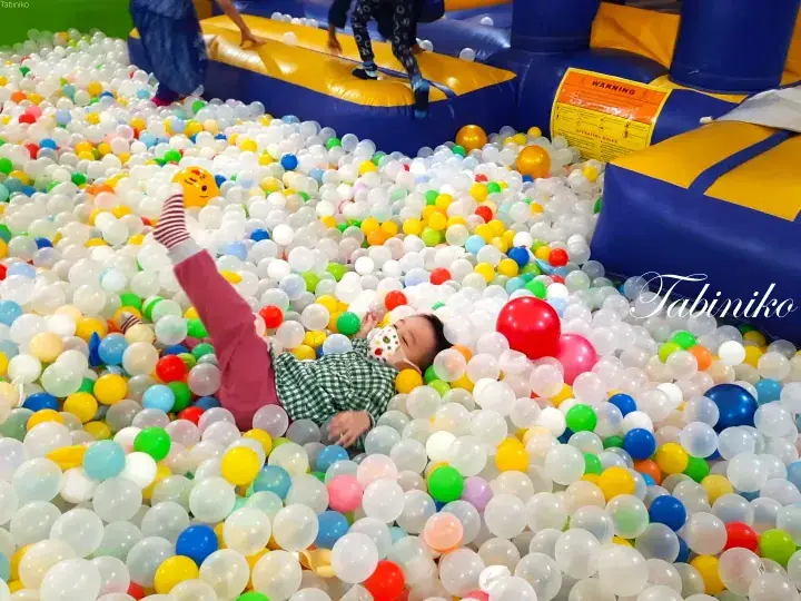 Child playing in a colorful ball pit at an indoor playground in Malaysia.