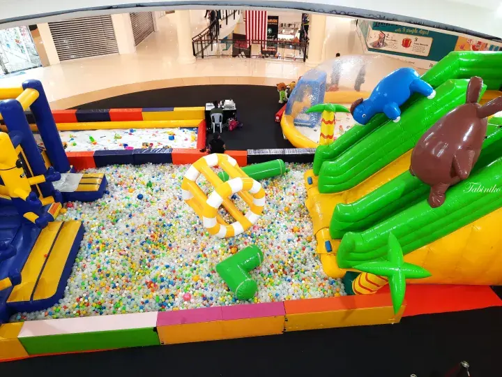 Colorful indoor playground with inflatable slides and ball pit at a shopping mall.