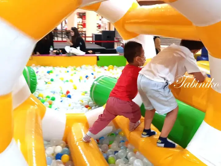 Children climbing on an inflatable structure at a ball pit play area.
