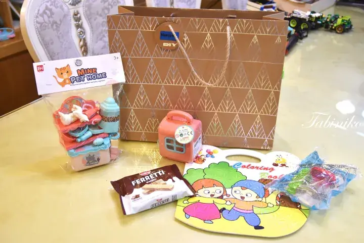 Children&rsquo;s party favors including a DIY pet home kit, coloring book, and snacks on a table.