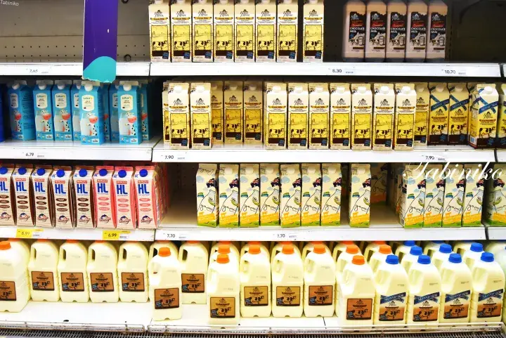 Refrigerated dairy shelves stocked with various milk cartons and bottles in a Malaysian supermarket.