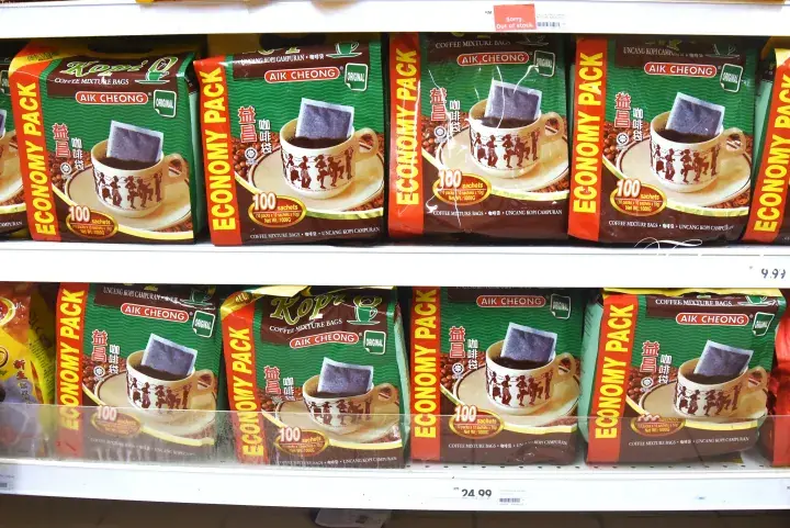 Shelves stocked with Aik Cheong economy pack coffee mix bags in a Malaysian grocery store.