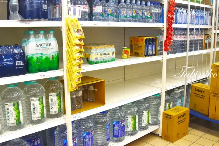 Shelves stocked with bottled water and beverages in a Malaysian grocery store.