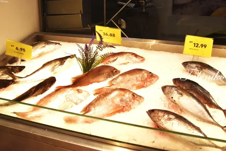 Fresh fish displayed on ice at a Malaysian seafood market with yellow price tags in Ringgit.