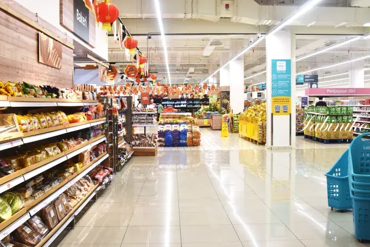 Aisles of a modern Malaysian supermarket with shelves stocked with snacks and festive red lanterns hanging from the ceiling.