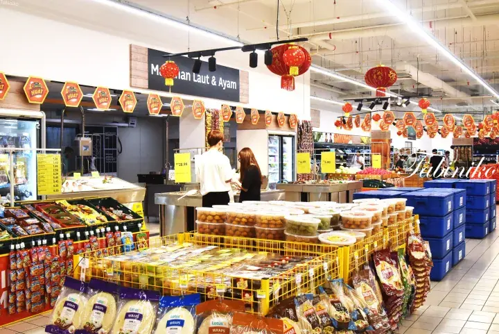 Interior of a Malaysian supermarket with fresh produce displays, hanging lanterns, and a seafood counter.