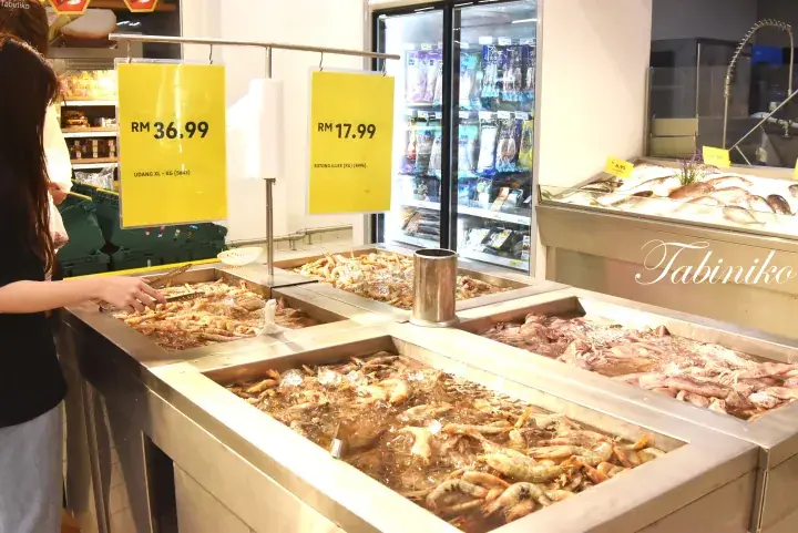 Fresh seafood displayed on ice at a supermarket counter with price signs showing RM 36.99 and RM 17.99.