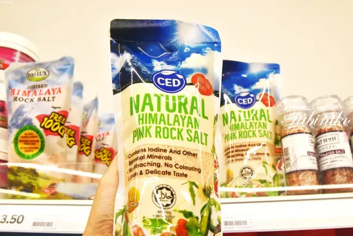 Hand holding a bag of CED Natural Himalayan Pink Rock Salt on a grocery store shelf in Malaysia.