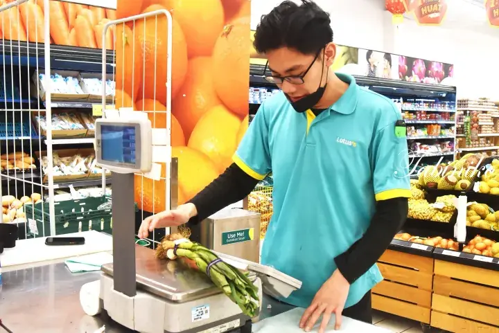 Lotus’s staff weighing fresh vegetables at a supermarket checkout counter in Malaysia.
