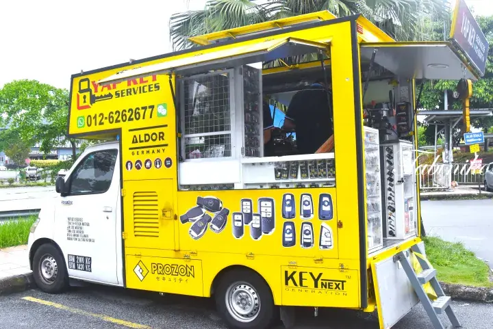 A bright yellow mobile car key cutting and programming van parked on a street in Malaysia.