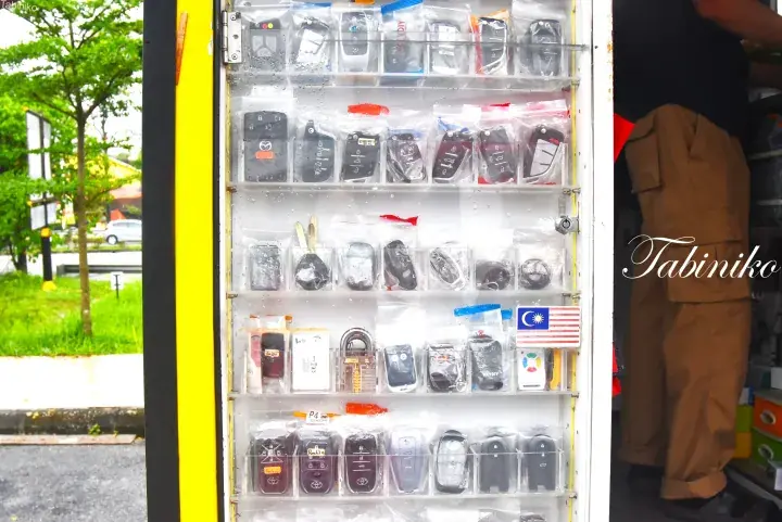 Display of various car key fobs and locks at a roadside stall in Malaysia.