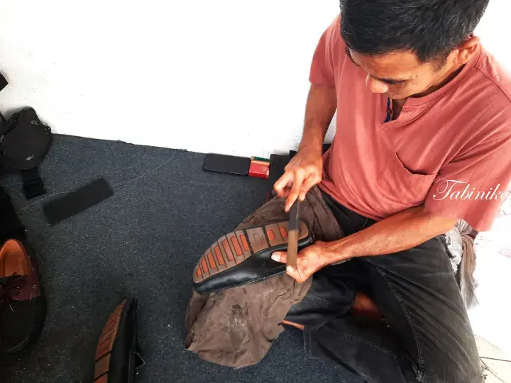 A skilled artisan carefully handcrafting a leather shoe in a traditional workshop setting.