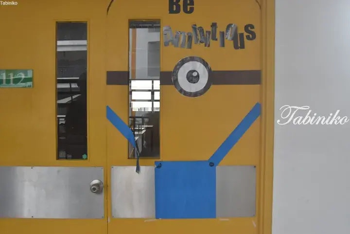 Yellow door decorated as a Minion character with a single eye and blue overalls.