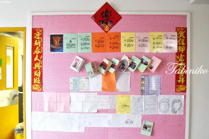 A pink bulletin board decorated with Chinese New Year couplets and festive items.