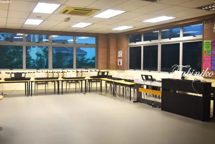 Empty classroom with rows of desks and chairs, large windows, and a black podium in a modern school setting.