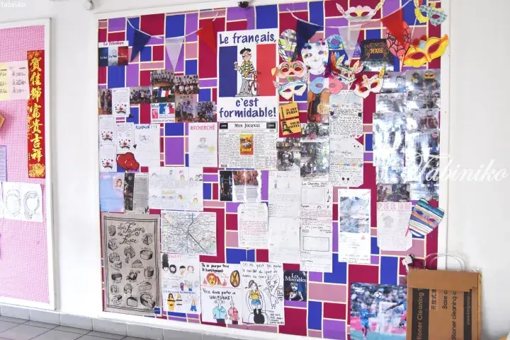 Colorful French language bulletin board with student projects, maps, and decorations in a Malaysian school hallway.