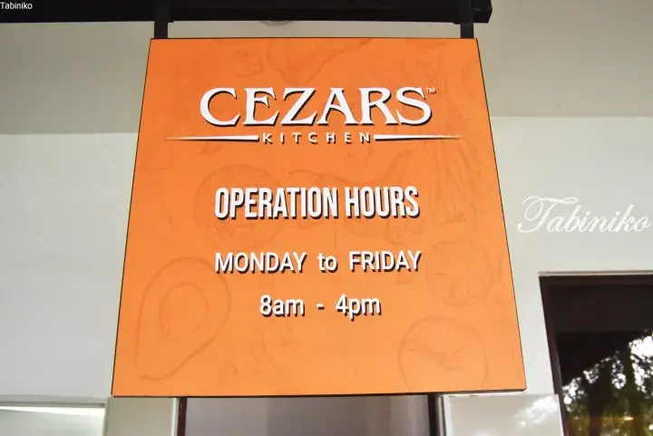 Orange sign for Cezars Kitchen showing operation hours Monday to Friday 8am to 4pm