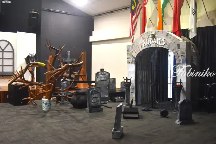 Halloween-themed event setup featuring a paper-mache Addams Family archway, tombstones, and spooky decorations.