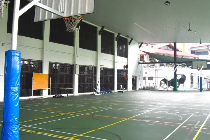 Covered basketball court with green flooring and yellow lines at a school facility in Malaysia.