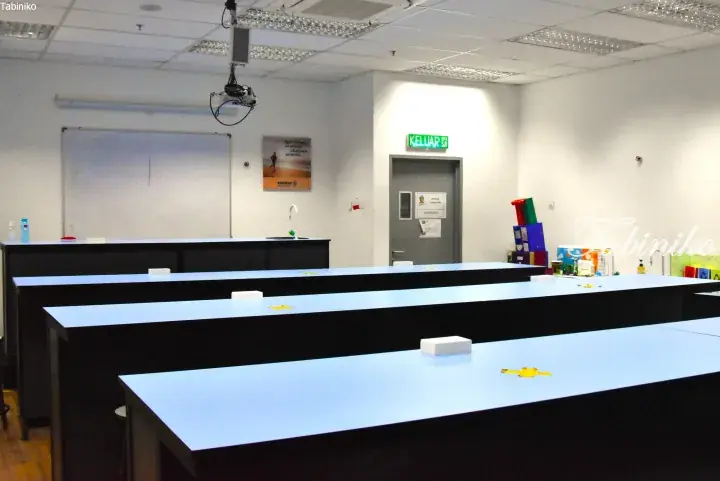 Rows of modern laboratory benches in a Sunway University physics lab with a whiteboard and exit sign.