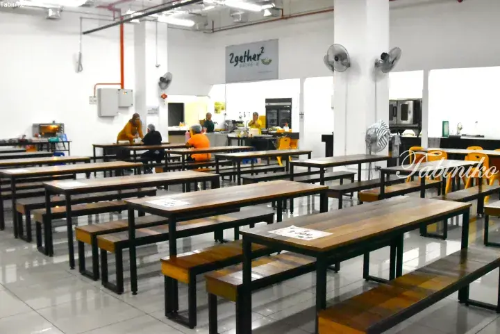 Spacious dining area with wooden tables and benches at 2gether2 community kitchen.