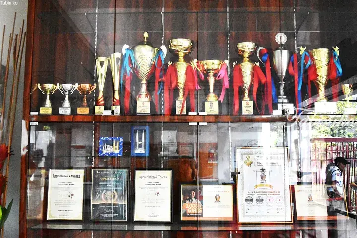 Display cabinet showcasing Campus Rangers International School trophies and awards, including the 2021 Malaysia Outstanding School Award.