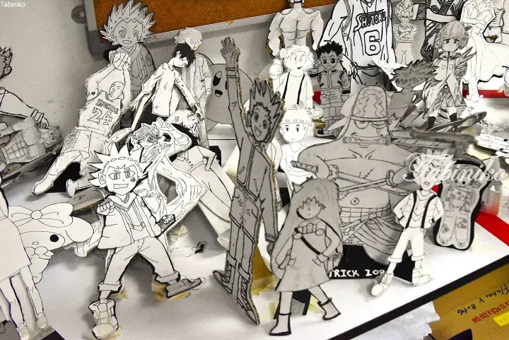 Hand-drawn cardboard cutouts of popular anime characters arranged on a display table.