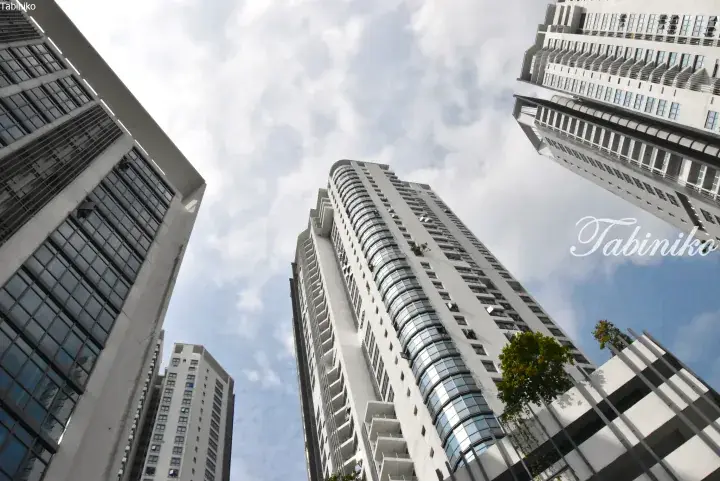 Low-angle view of modern white high-rise residential buildings against a cloudy sky in Malaysia