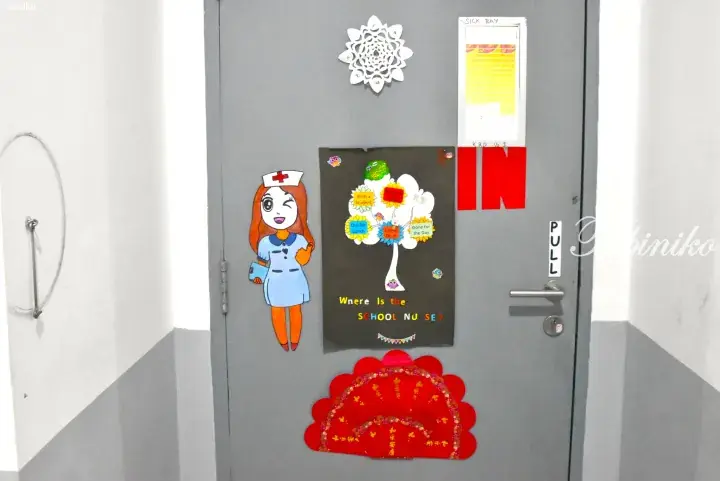 Grey school nurse&rsquo;s office door with a cartoon nurse, a tree chart showing student locations, and a red Chinese New Year decoration.