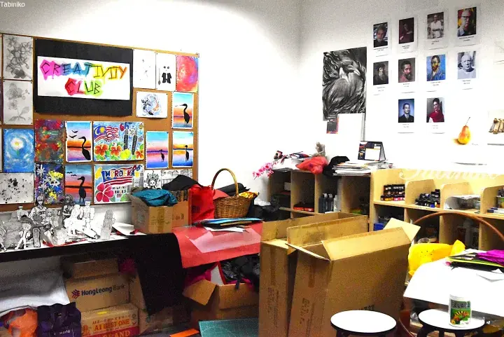 A creative arts studio in Malaysia filled with student artwork, art supplies, and boxes, featuring a &lsquo;Creativity Club&rsquo; sign.