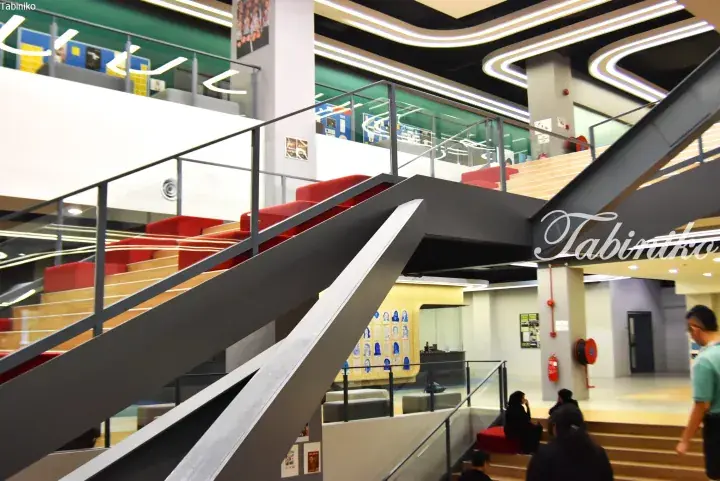 Modern interior staircase with red seating and glass railings in a contemporary Malaysian building.