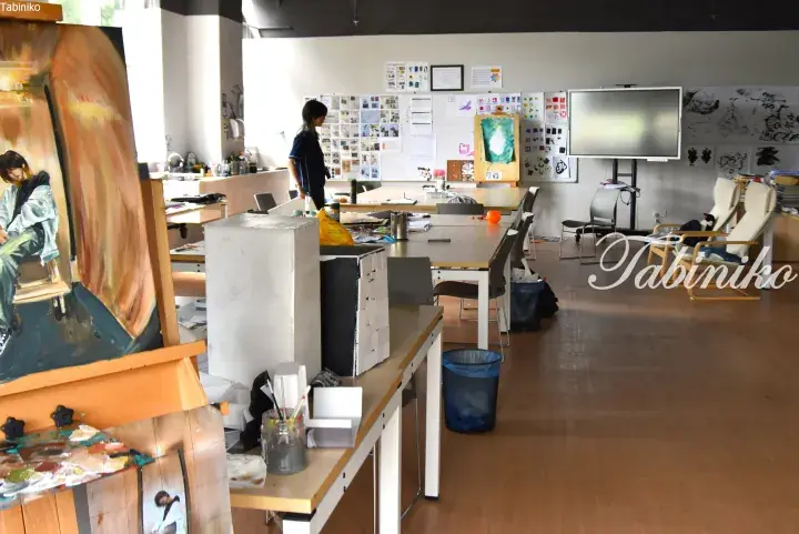 Bright art studio with easels, paintings, and work tables in a creative workspace.