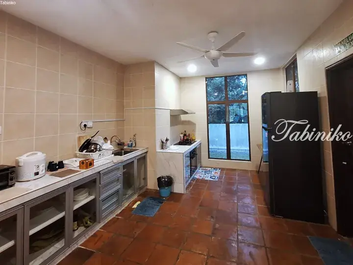 Spacious kitchen with terracotta floor tiles, stainless steel cabinets, and a large window overlooking greenery.
