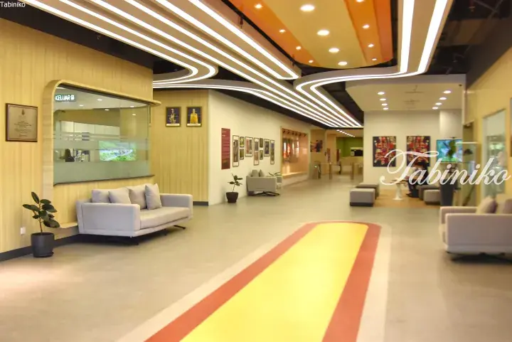 Modern interior hallway with curved LED ceiling lights, yellow and red floor accents, and comfortable seating areas.
