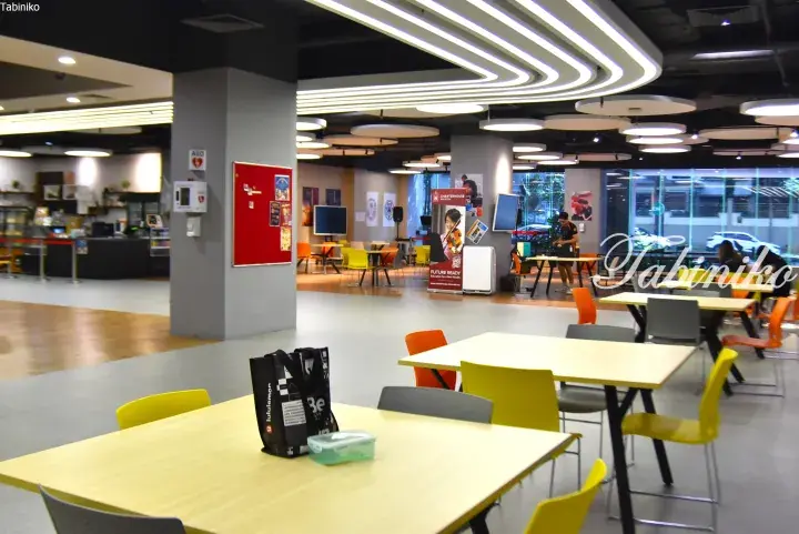 Modern school cafeteria with yellow tables and chairs, featuring a food counter and Charterhouse Malaysia banner.
