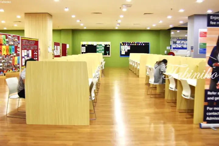 Modern study area with wooden study pods and green walls at a Malaysian educational institution.