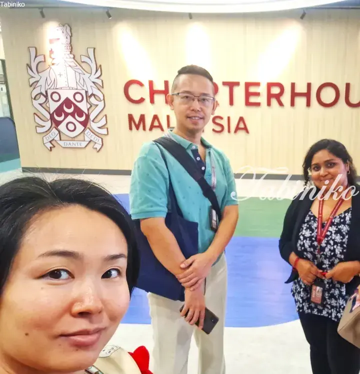 Visitors pose for a photo in front of the Charterhouse Malaysia sign and crest.
