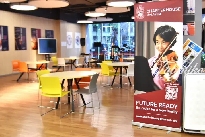 Modern school lounge with colorful tables and chairs, featuring a Charterhouse Malaysia banner promoting future-ready education.
