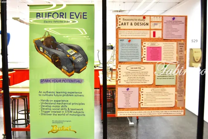 Educational display featuring a Bufori EViE electric vehicle poster and an Art & Design career information board.