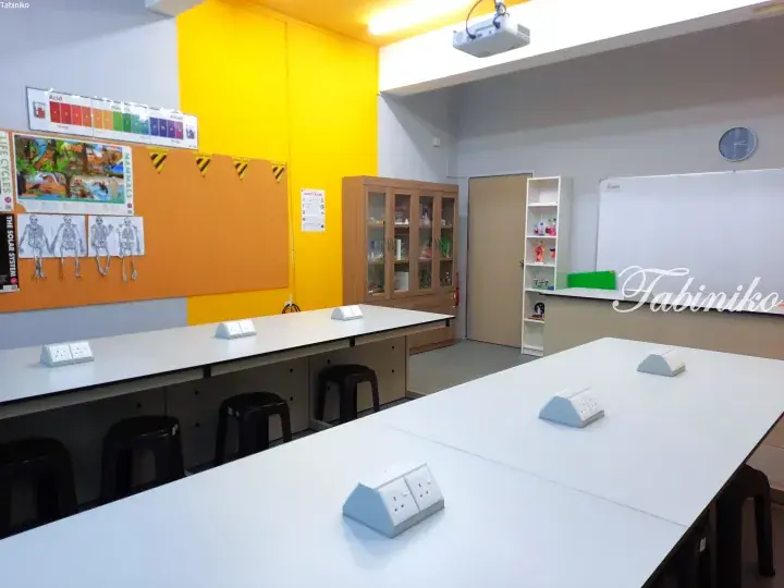 Modern science laboratory with white workstations, power outlets, and educational posters on yellow and orange walls.