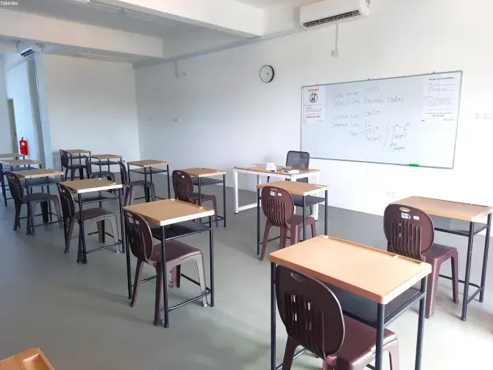 Empty exam room with desks and chairs, whiteboard showing Business Studies syllabus details and centre number MY397.