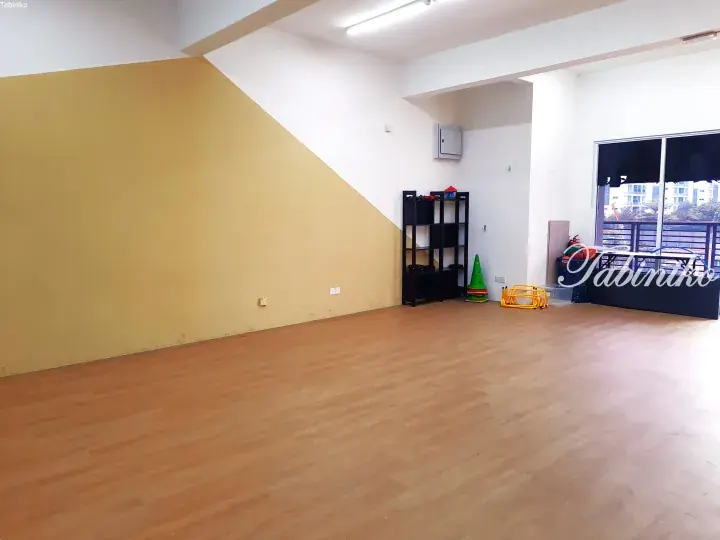 Spacious room with wooden flooring, yellow accent wall, and children&rsquo;s play equipment near a balcony window.
