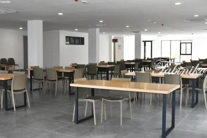 Spacious modern dining hall with wooden tables and grey chairs in a new property.