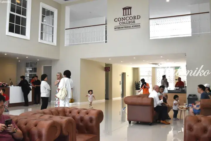 Bright lobby of Concord College International School with parents and children in a spacious, modern interior.