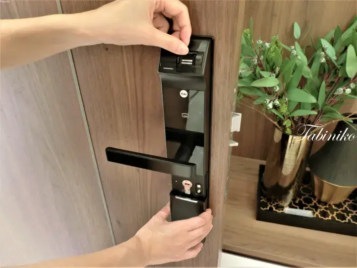 Person installing a Yale smart lock on a wooden door in a modern Malaysian property.