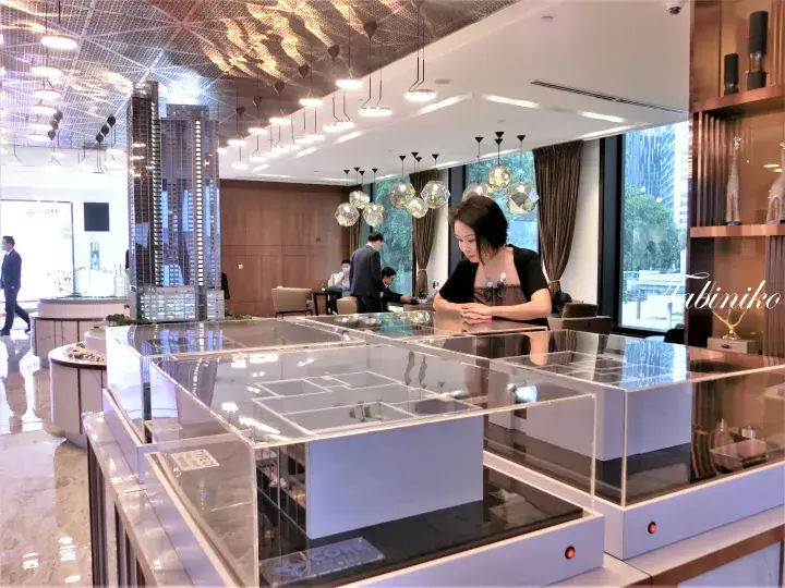 Woman examining architectural models at a modern property sales gallery in Kuala Lumpur.