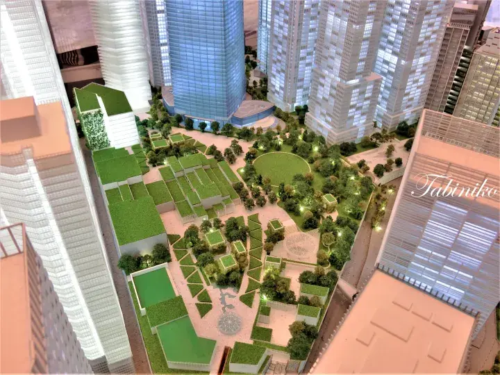 Architectural model of a modern mixed-use development featuring a central green park surrounded by high-rise towers.